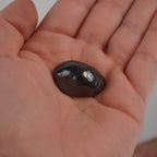 Hämatit Trommelstein in einer geöffneten Hand gehalten