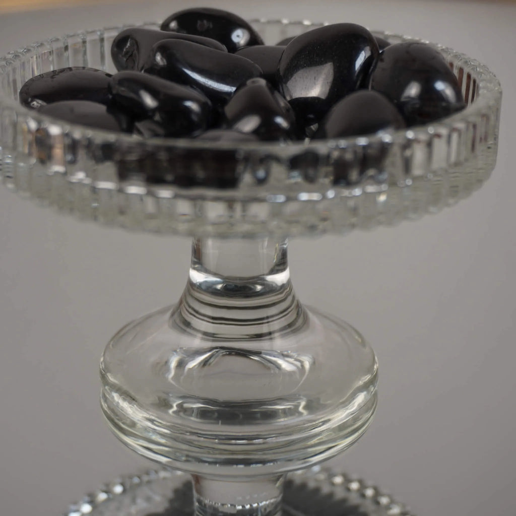 Mehrere Hämatit Trommelsteine in einem erhöhten Glaskelch präsentiert