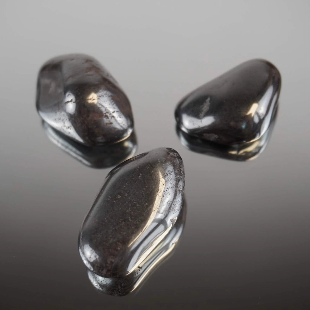 Drei Hämatit Trommelsteine mit spiegelnder Oberfläche auf glänzender Unterlage