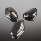 Drei Hämatit Trommelsteine mit spiegelnder Oberfläche auf glänzender Unterlage