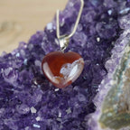 Roter Karneol Herzanhänger an 925 Silberkette, dekoriert auf violettem Amethyst