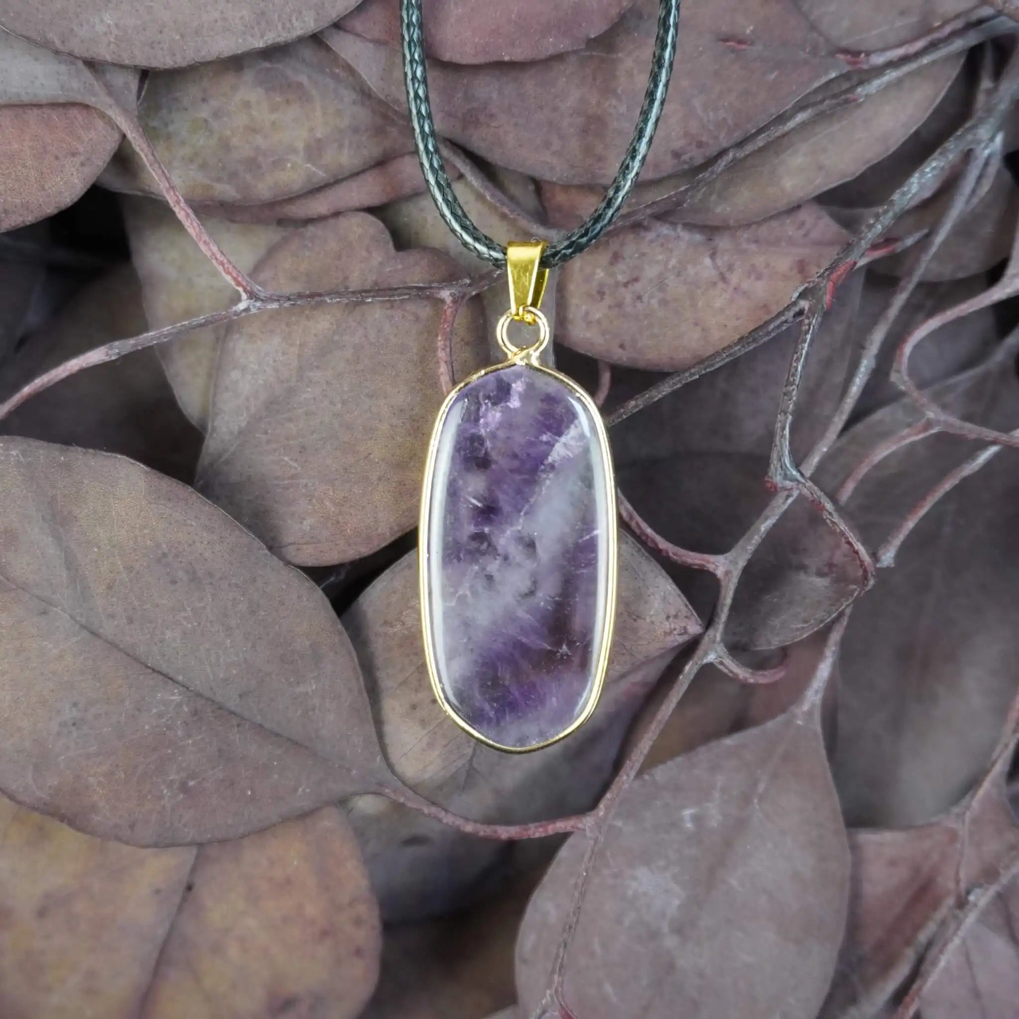 Halskette mit Amethyst Anhänger auf braunen Blättern