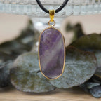 Halskette mit Amethyst Anhänger vor Glasgefäß mit Blättern