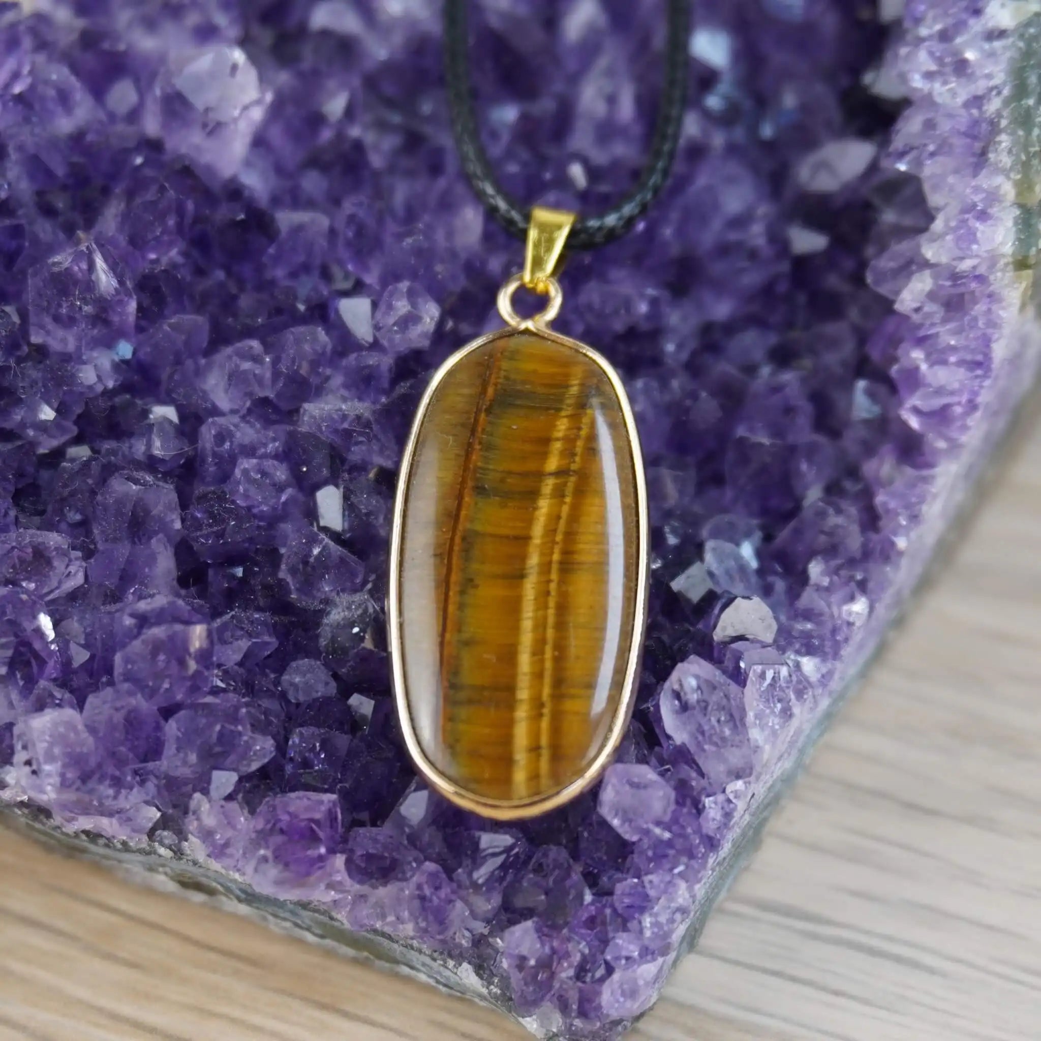 Tigerauge Halskette mit goldfarbener Umrandung auf violettem Amethyst-Hintergrund