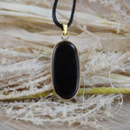 Schwarzer Onyx-Anhänger in goldfarbener Fassung dekoriert mit Naturmaterialien