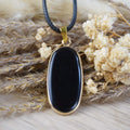 Halskette mit schwarzem Onyx-Anhänger zwischen getrockneten Blüten und Gräsern