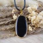 Halskette mit schwarzem Onyx-Anhänger zwischen getrockneten Blüten und Gräsern