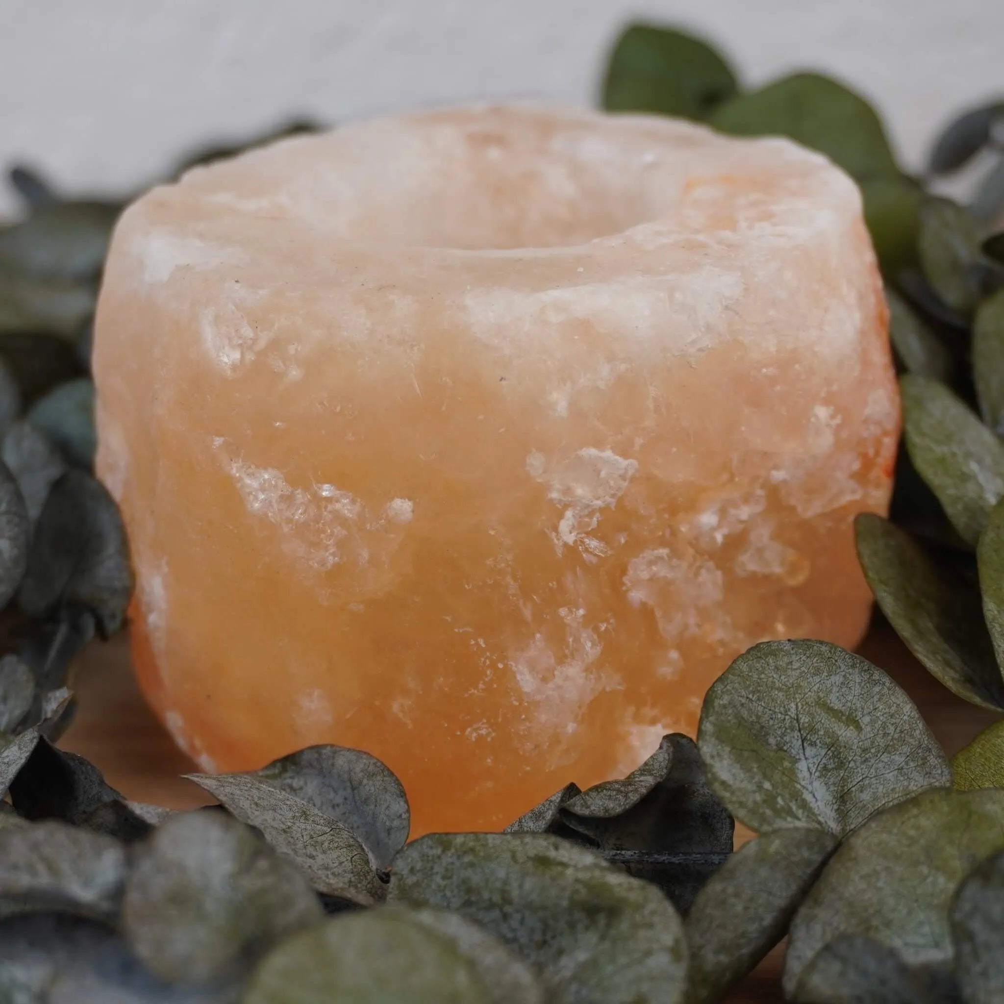 Himalaya Salzkristall Kerzenhalter umgeben von grünen Eukalyptusblättern