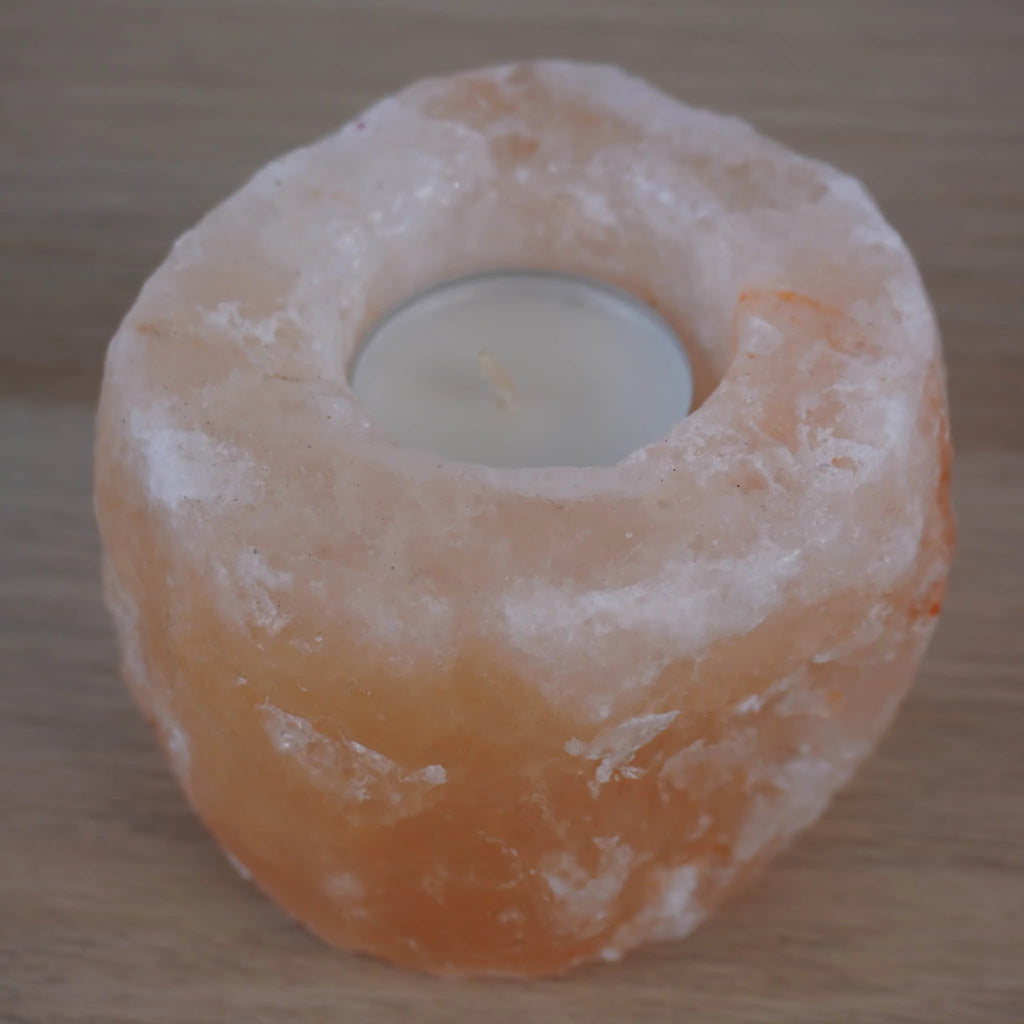 Himalaya Salzkristall Kerzenhalter mit eingesetztem Teelicht auf Holzuntergrund