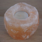 Himalaya Salzkristall Kerzenhalter mit eingesetztem Teelicht auf Holzuntergrund