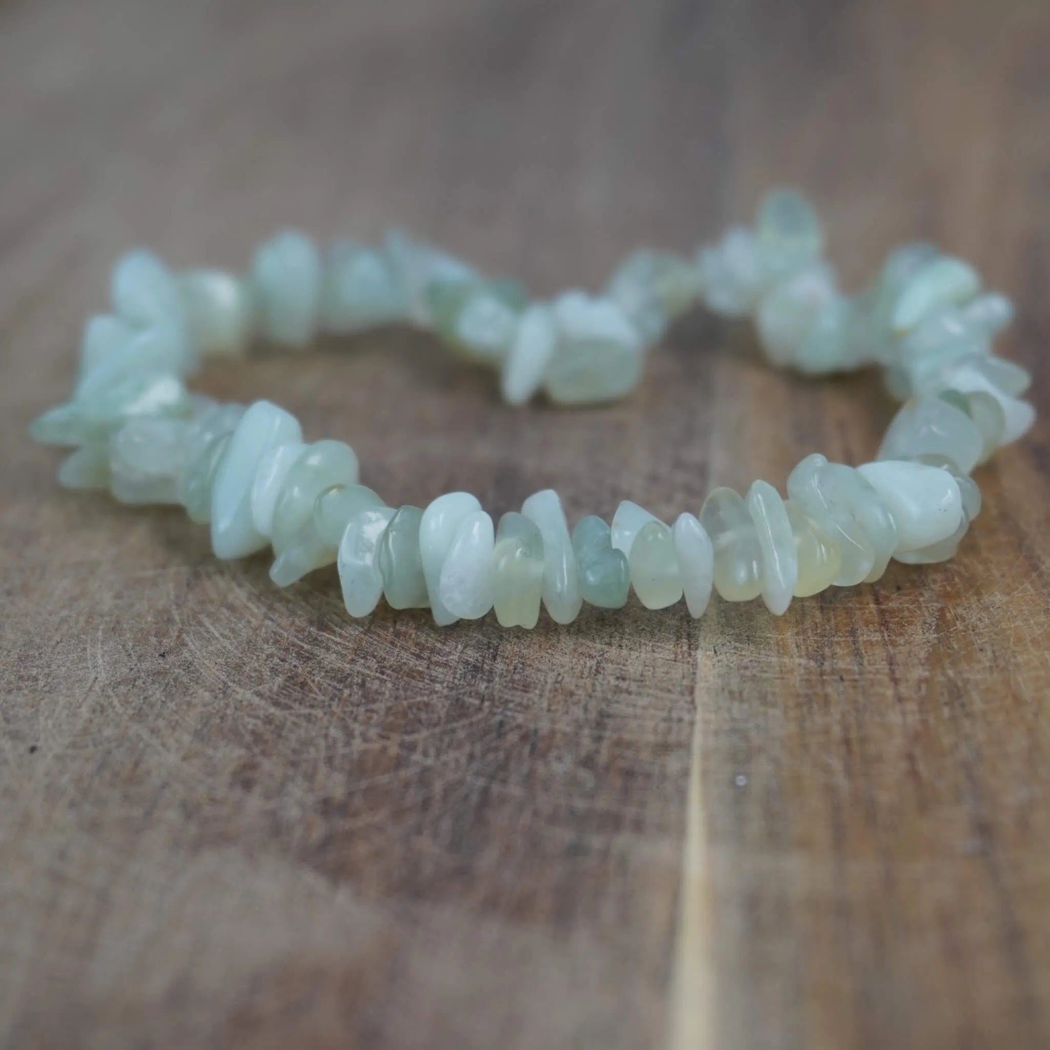 Jade Splitterarmband dezent dekoriert auf warmer und rustikaler Holzoberfläche