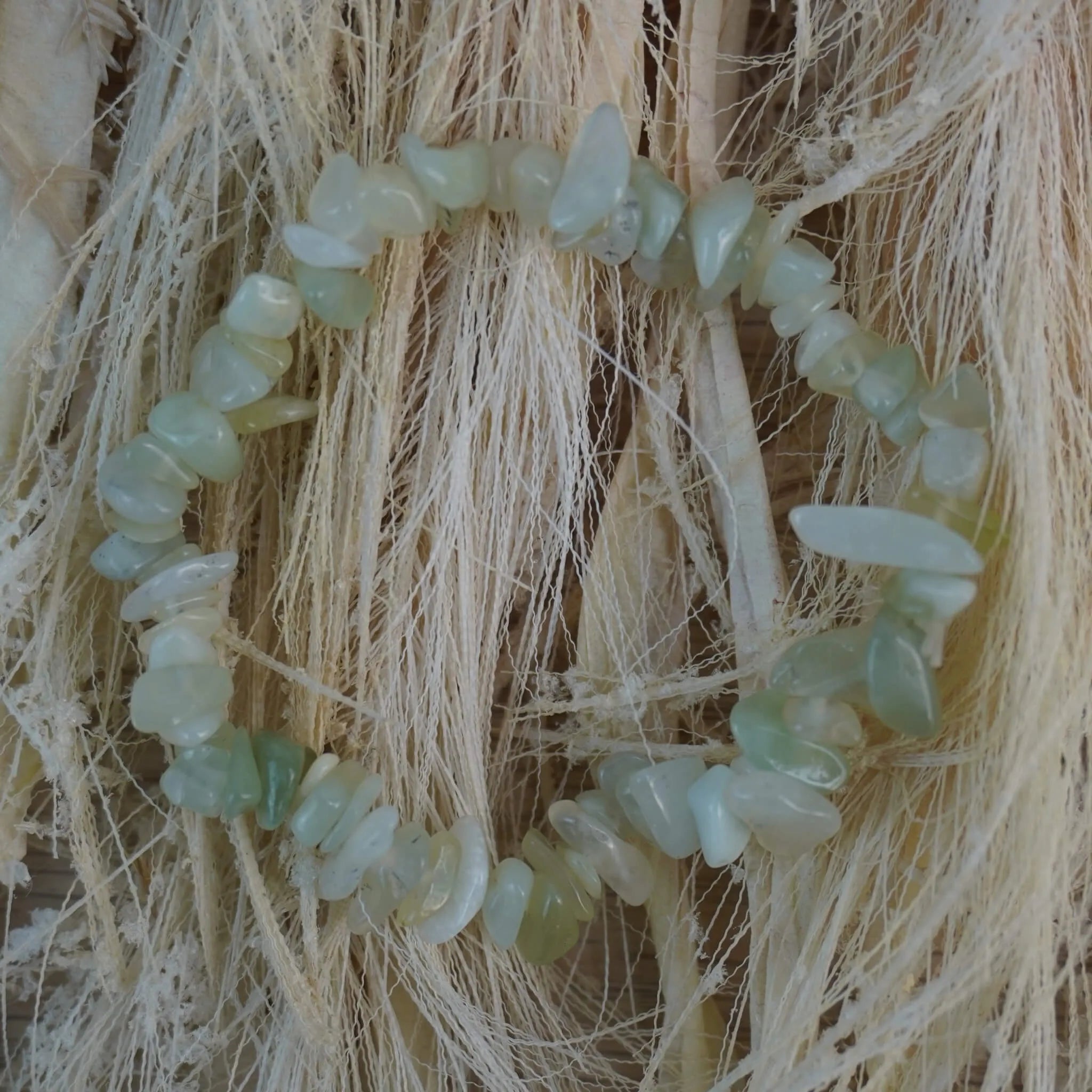 Jade Splitterarmband auf hellem Naturfaserdekor mit feiner Struktur