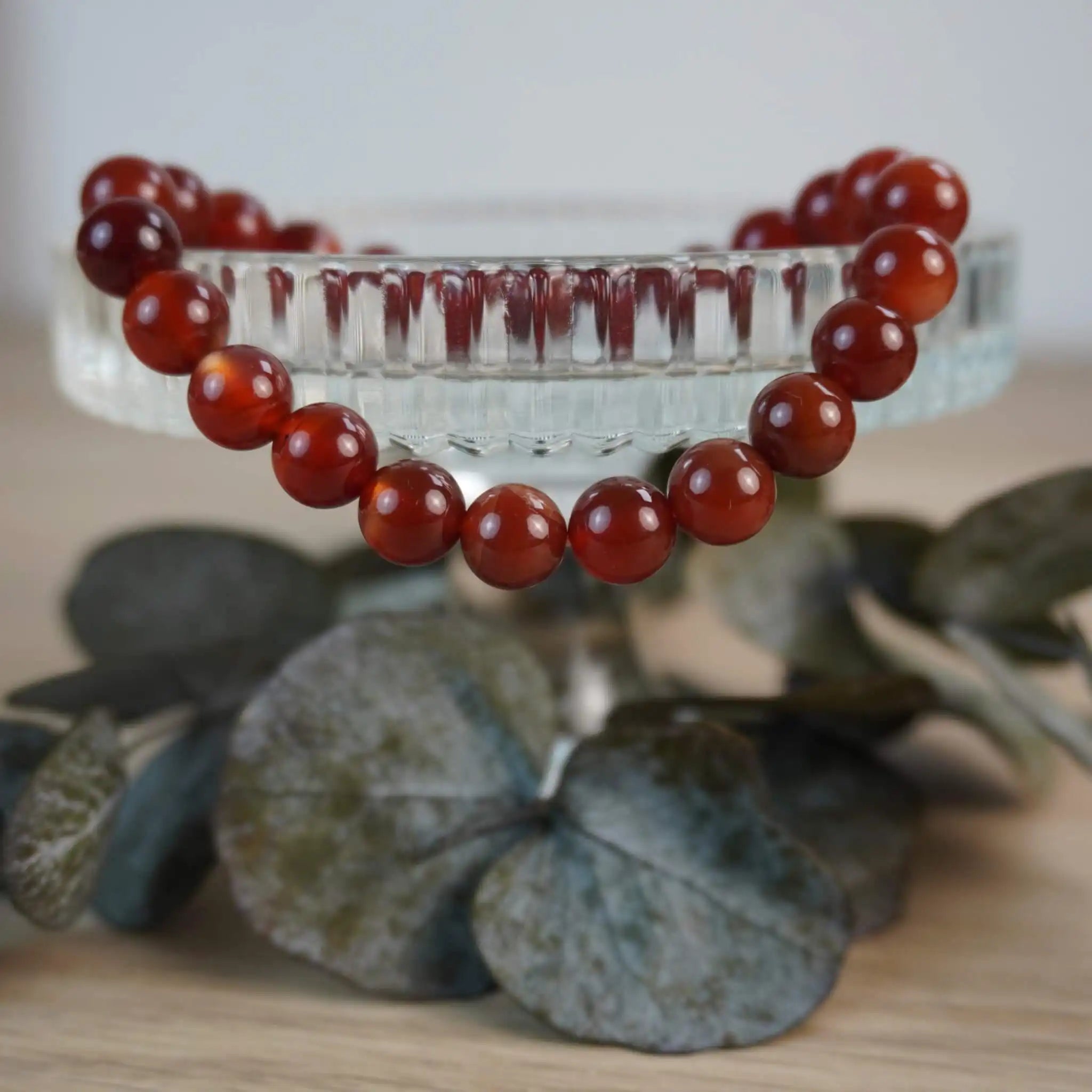 Karneol Kugelarmband dekoriert auf Glasgefäß mit Blättern