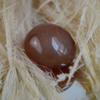 Karneol Trommelstein in warmem Orange auf hellen Naturfasern