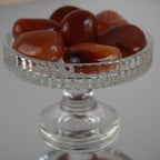 Mehrere glänzende Karneol Trommelsteine in einem erhöhten Glaskelch