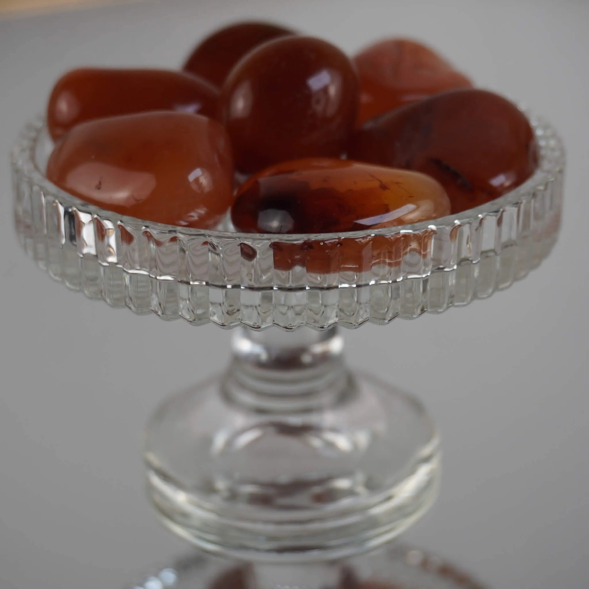 Mehrere glänzende Karneol Trommelsteine in einem erhöhten Glaskelch