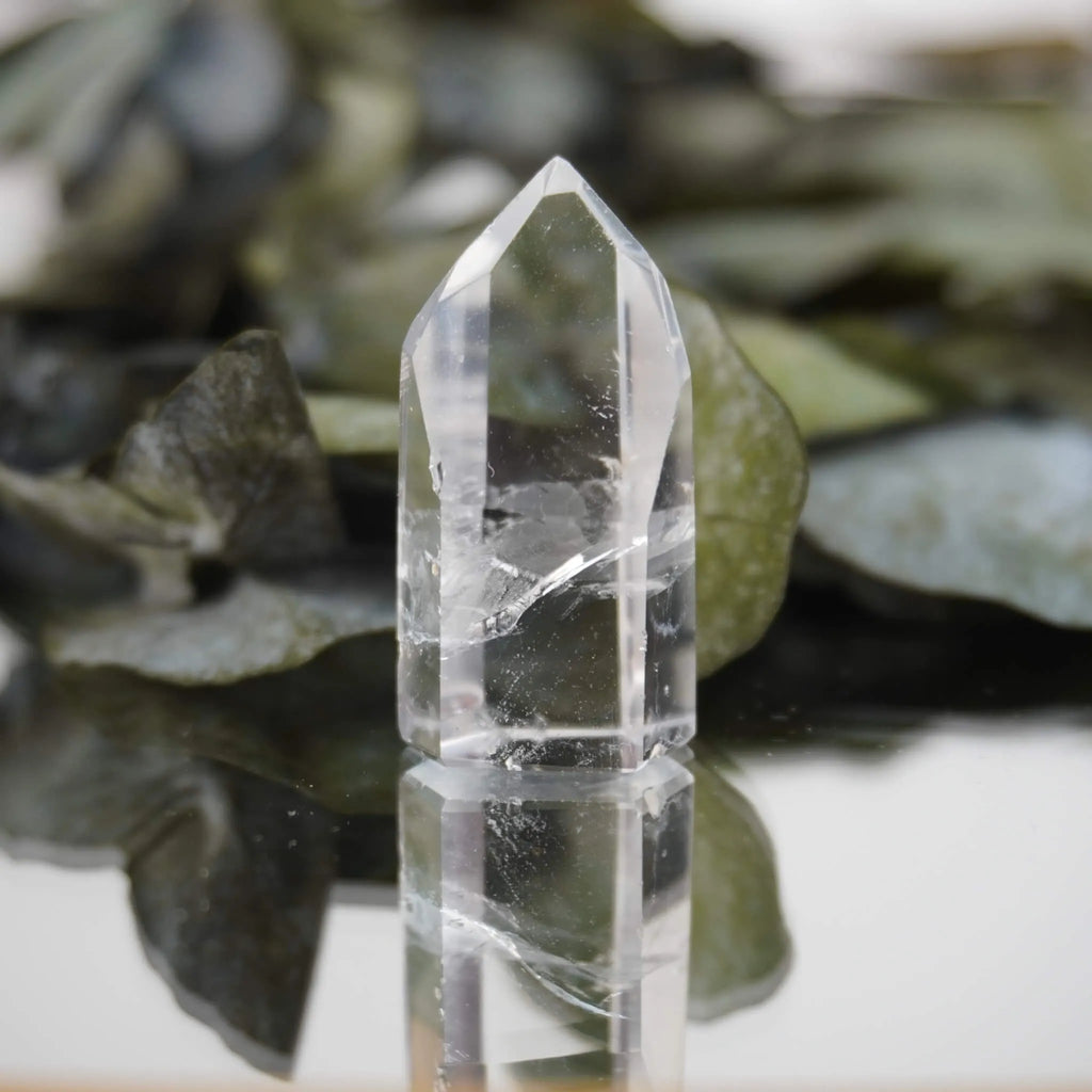 Klare Bergkristall Spitze mit Spiegelung auf Glas vor grünen Eukalyptusblättern dekoriert