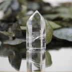 Klare Bergkristall Spitze mit Spiegelung auf Glas vor grünen Eukalyptusblättern dekoriert