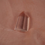 Polierte klare Bergkristall Spitze liegend auf zart rosafarbenem Stoff