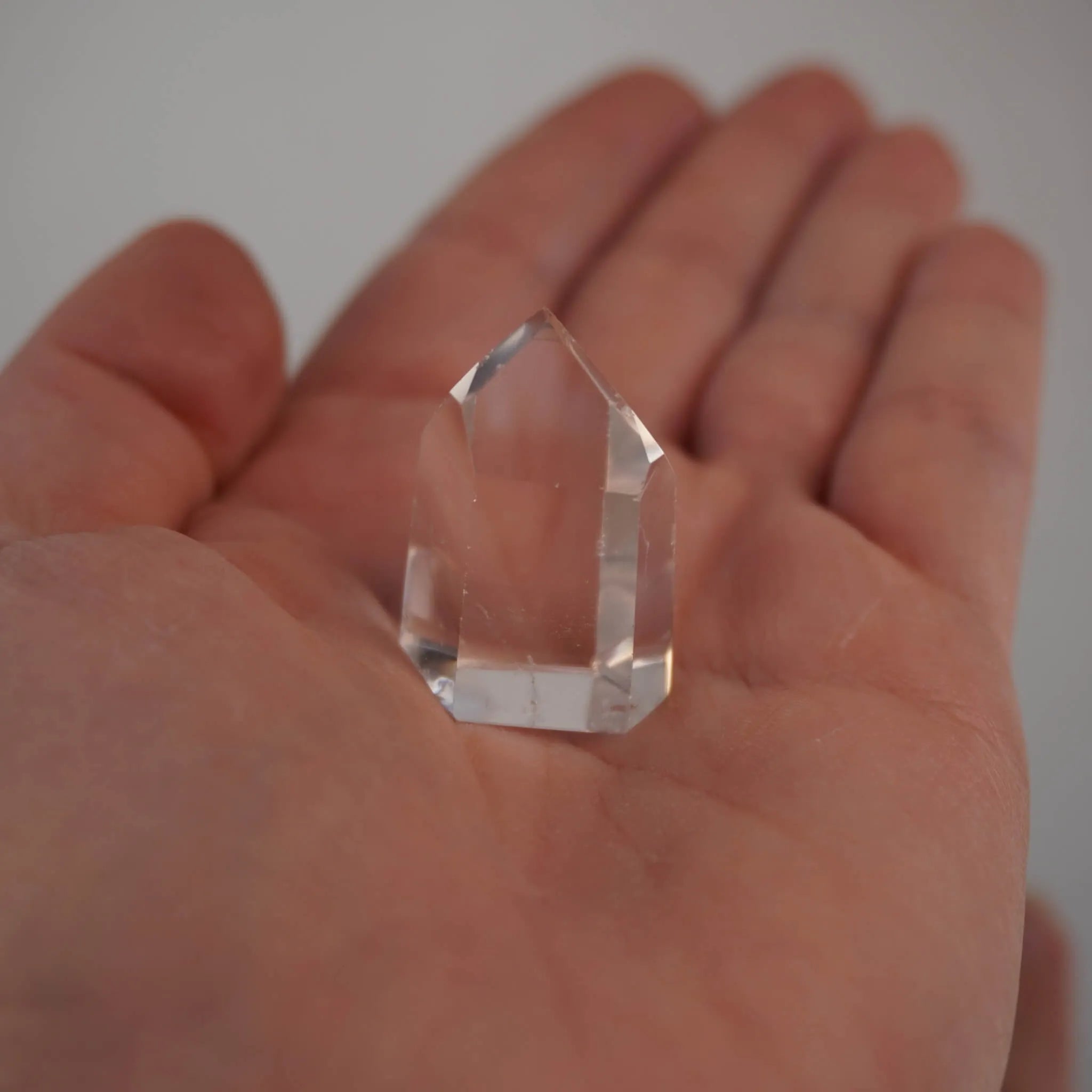 Klare Bergkristall Spitze in einer offenen Handfläche gehalten