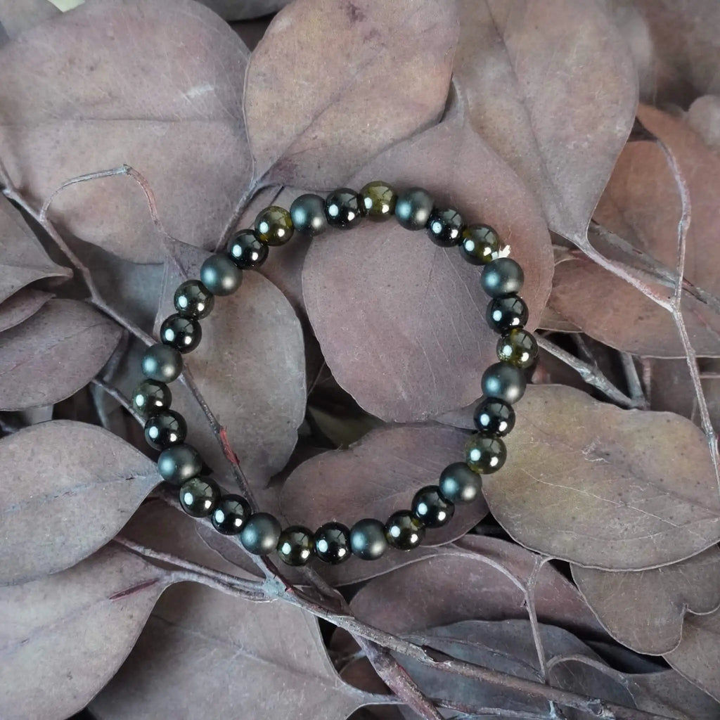 Kugelarmband aus Onyx, Obsidian und Turmalin auf einem Bett aus Blättern