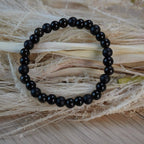 Kugelarmband aus Onyx, Obsidian und Turmalin auf hellem Trockengras dekoriert