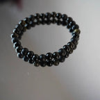 Kugelarmband aus Onyx, Obsidian und Turmalin auf spiegelnder Fläche