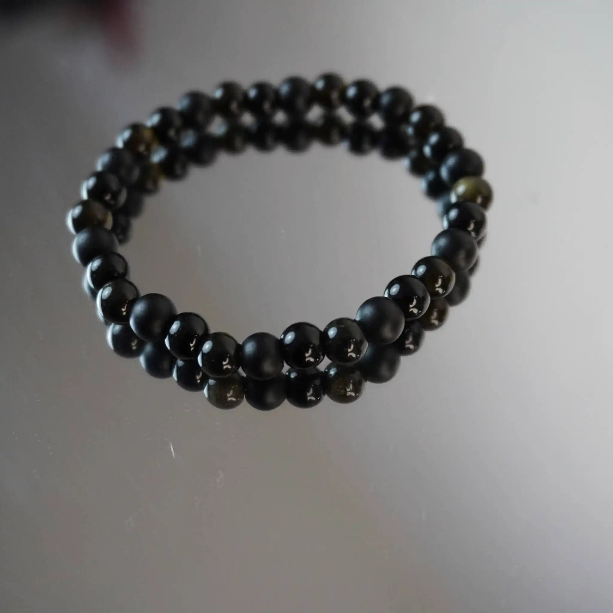 Kugelarmband aus Onyx, Obsidian und Turmalin auf spiegelnder Fläche
