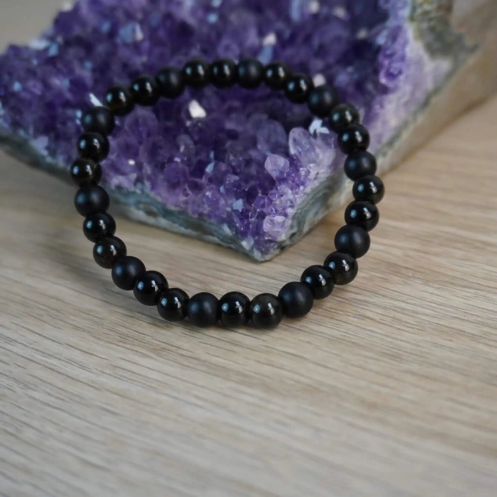 Kugelarmband aus Onyx, Obsidian und Turmalin vor einem Amethyst-Dekostein