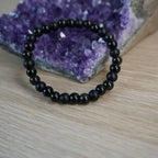 Kugelarmband aus Onyx, Obsidian und Turmalin vor einem Amethyst-Dekostein