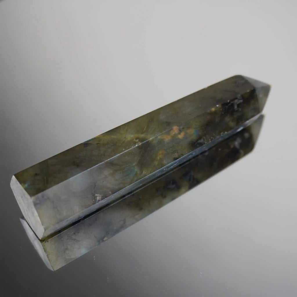 Labradorit Obelisk mit schimmernder Reflexion auf glänzender Oberfläche