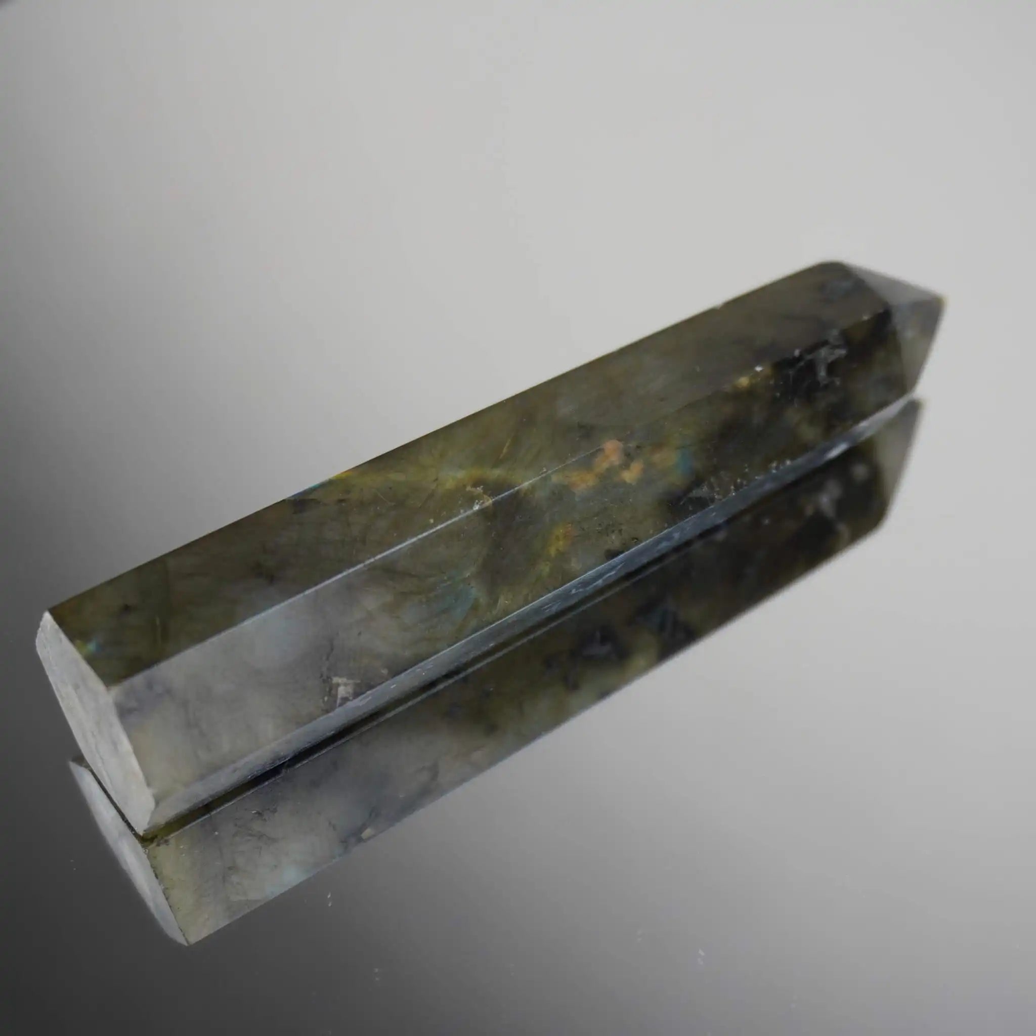 Labradorit Obelisk mit schimmernder Reflexion auf glänzender Oberfläche