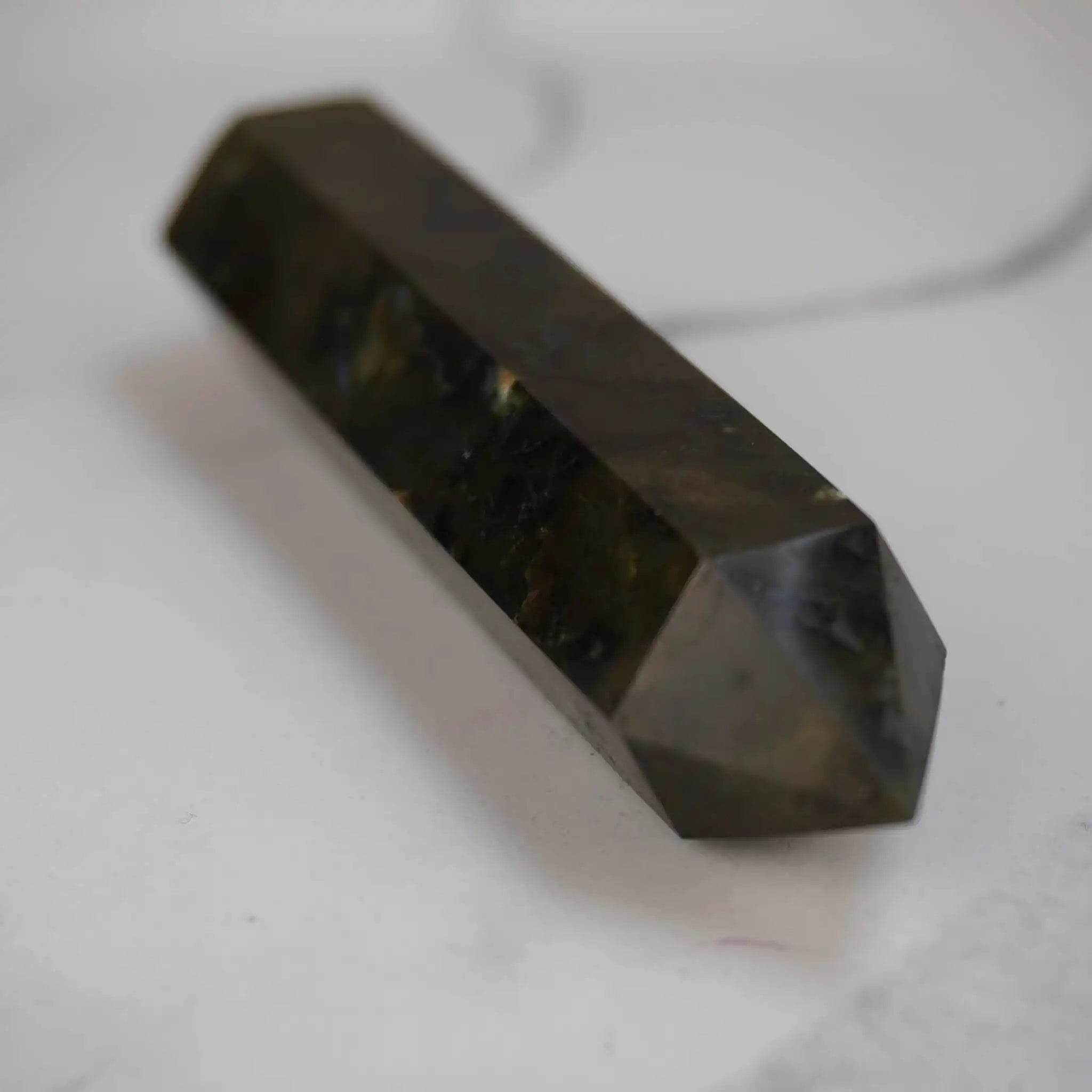 Dunkler Labradorit Obelisk Edelstein seitlich auf weißem Marmor