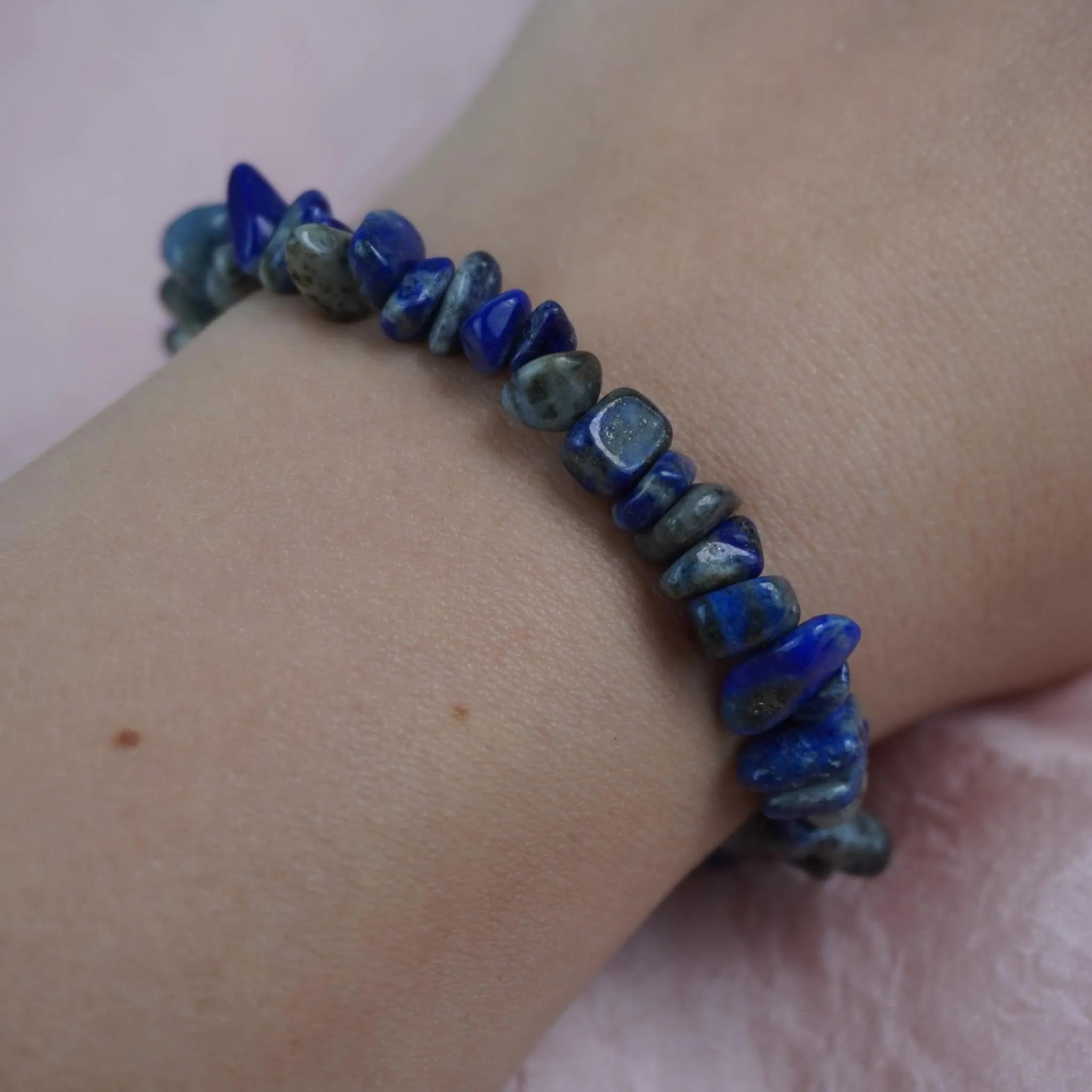 Lapislazuli‑Splitterarmband am Handgelenk vor zartrosa Hintergrund