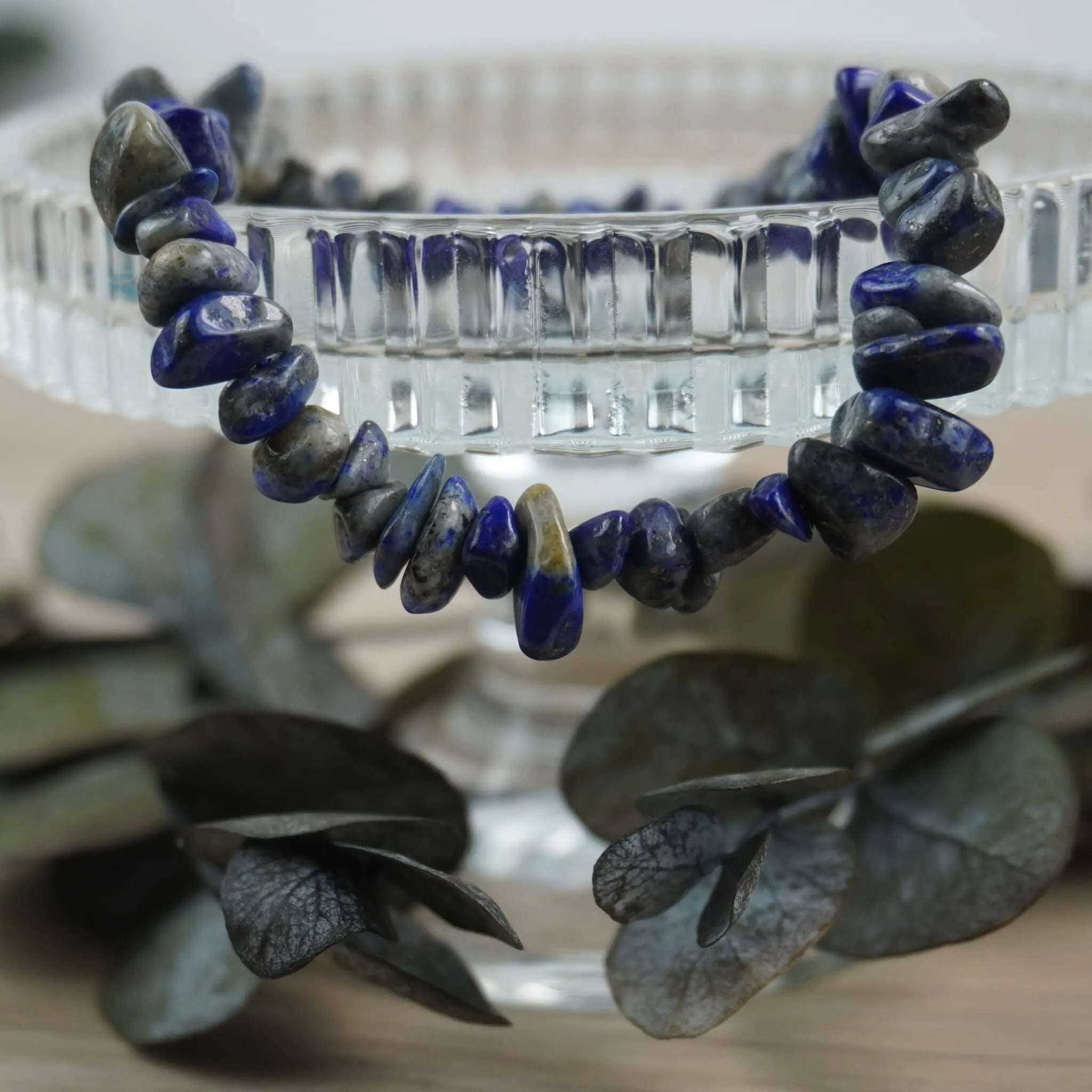Lapislazuli‑Splitterarmband edel in Szene gesetzt auf Glas-Schale mit Eukalyptus