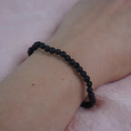 Lavastein Kugelarmband schlicht am Handgelenk vor rosa Hintergrund