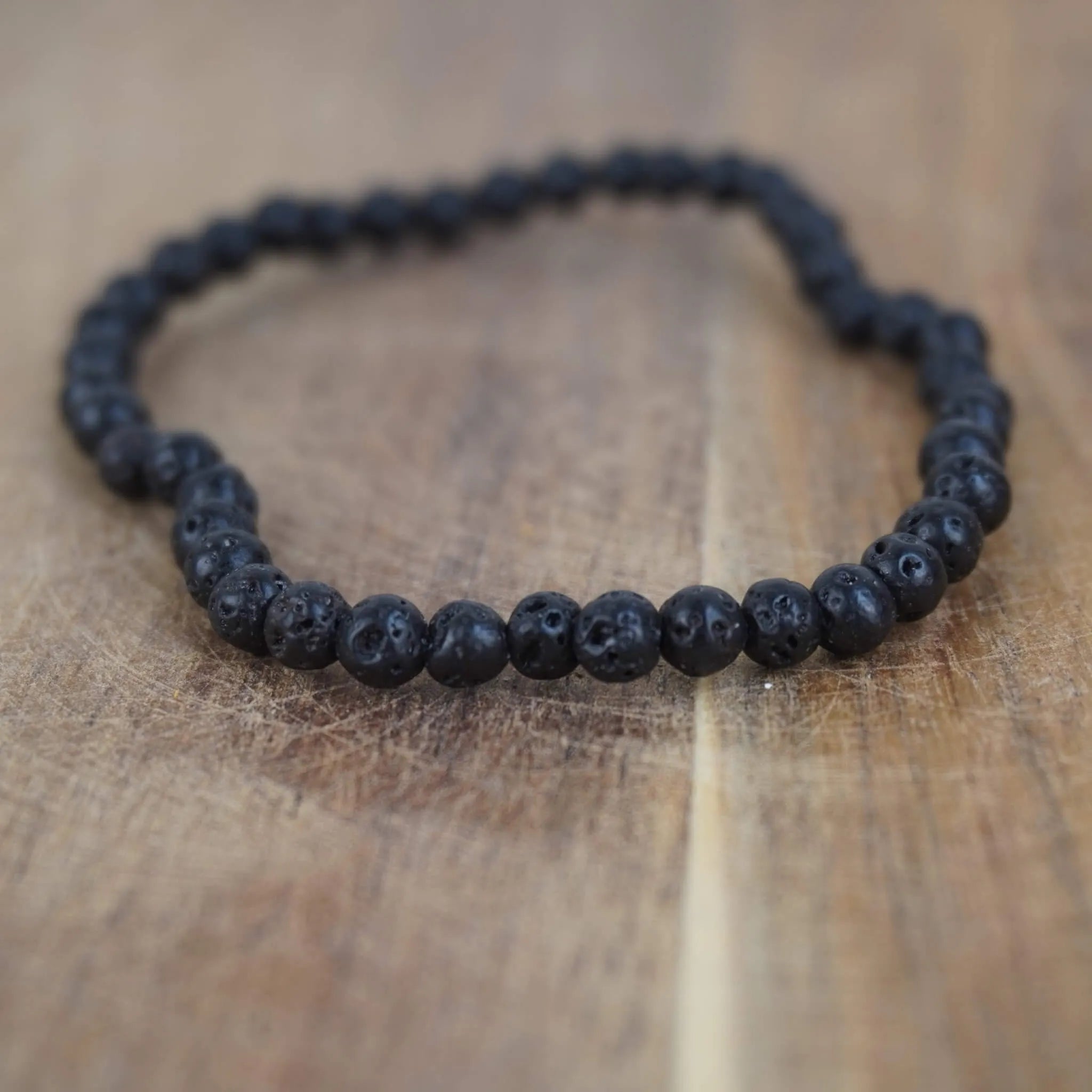 Lavastein Kugelarmband auf rustikalem Holzuntergrund im Detail