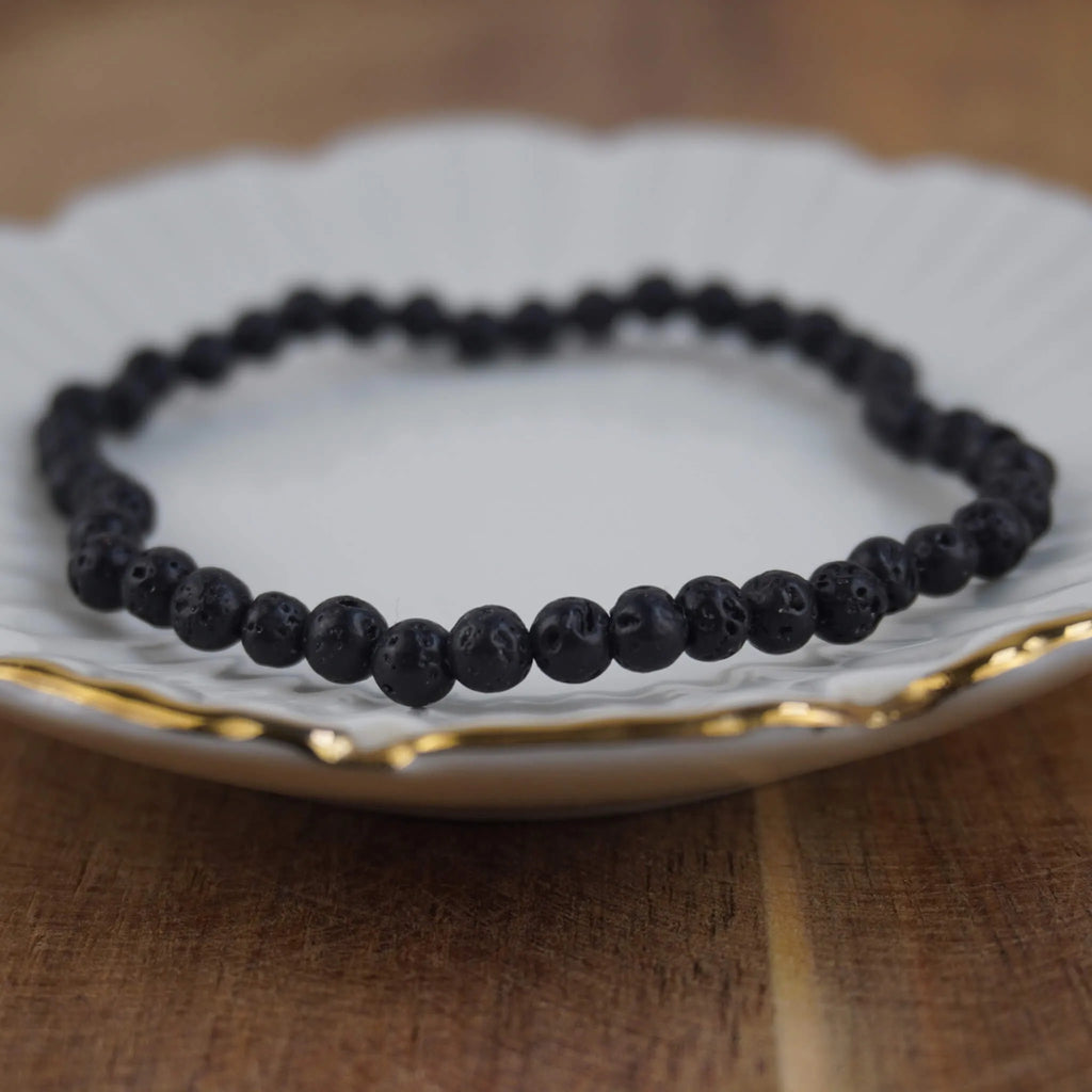 Lavastein Kugelarmband auf weißem Teller mit elegantem Goldrand