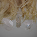 Drei lemurianische Quarz Spitzen vor hellen Naturfasern mit Spiegelung