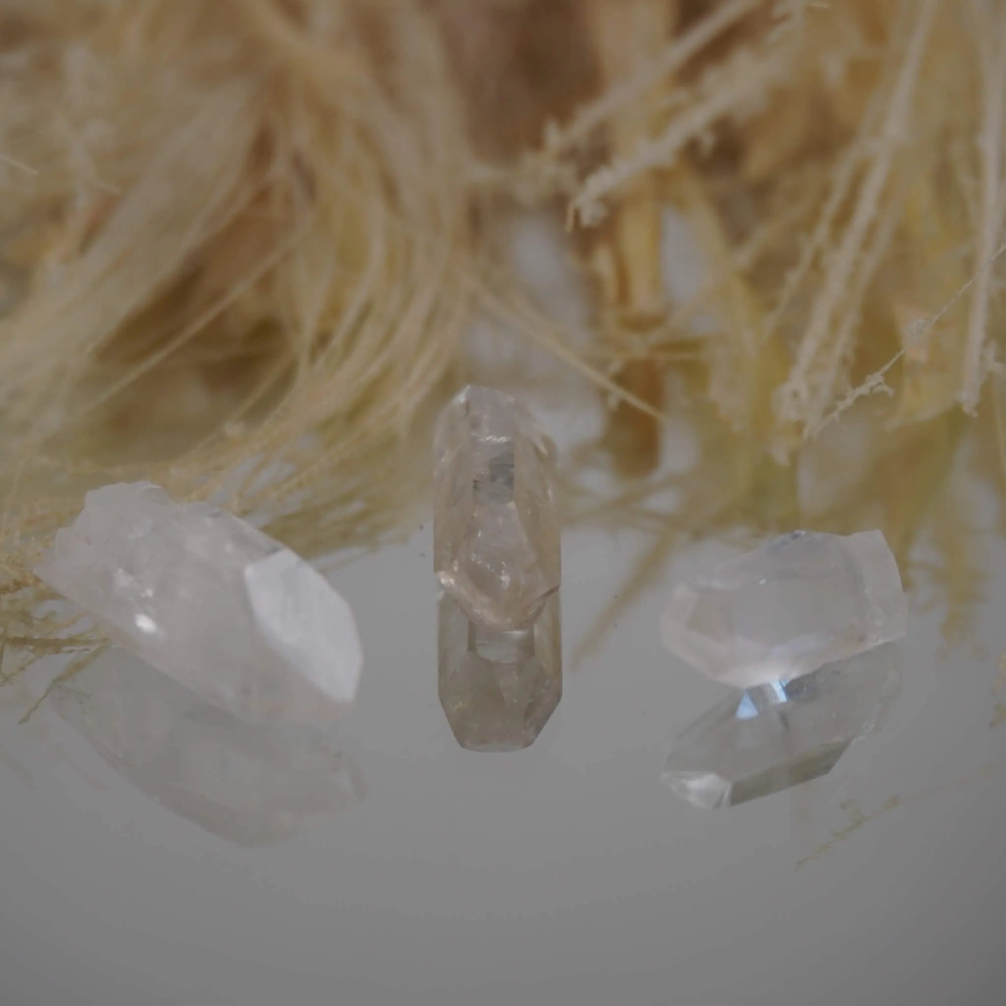 Drei lemurianische Quarz Spitzen vor hellen Naturfasern mit Spiegelung
