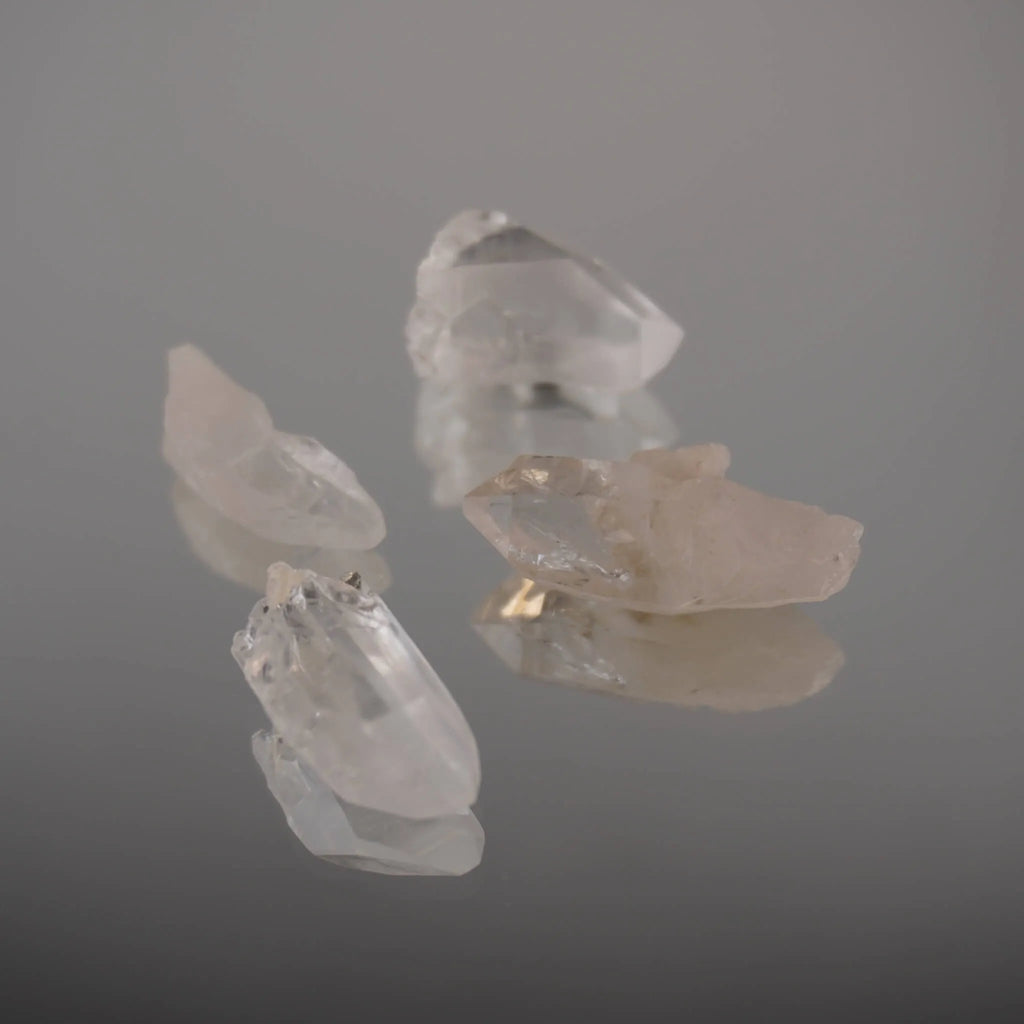 Vier lemurianische Quarz Spitzen mit Spiegelung auf glänzender Fläche