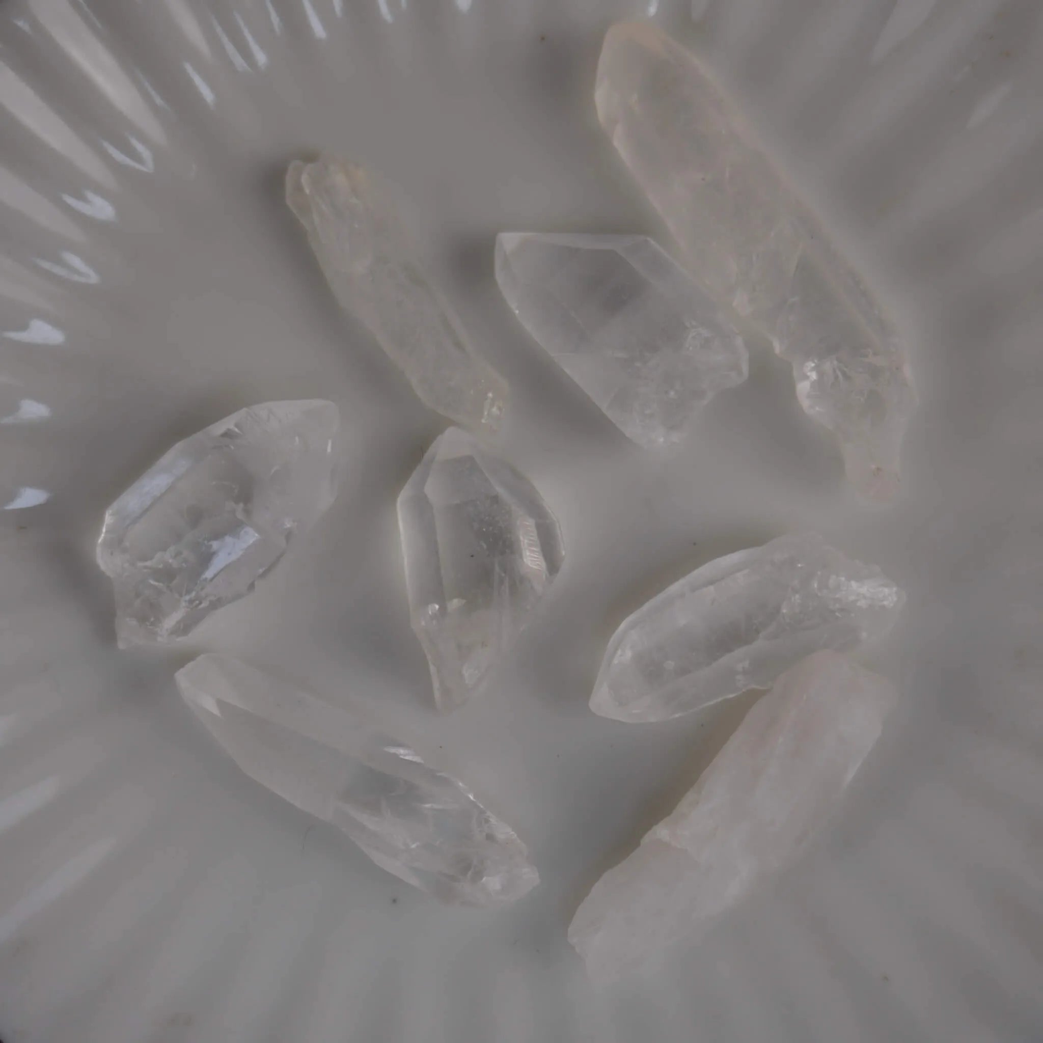 Mehrere lemurianische Quarz Spitzen auf weißem Teller von oben fotografiert