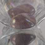 Lila Angel Aura Trommelstein in Glasschale mit Reflexion in Nahaufnahme