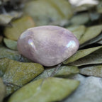 Lila Angel Aura Trommelstein auf grünen Blättern mit zartem Schimmer