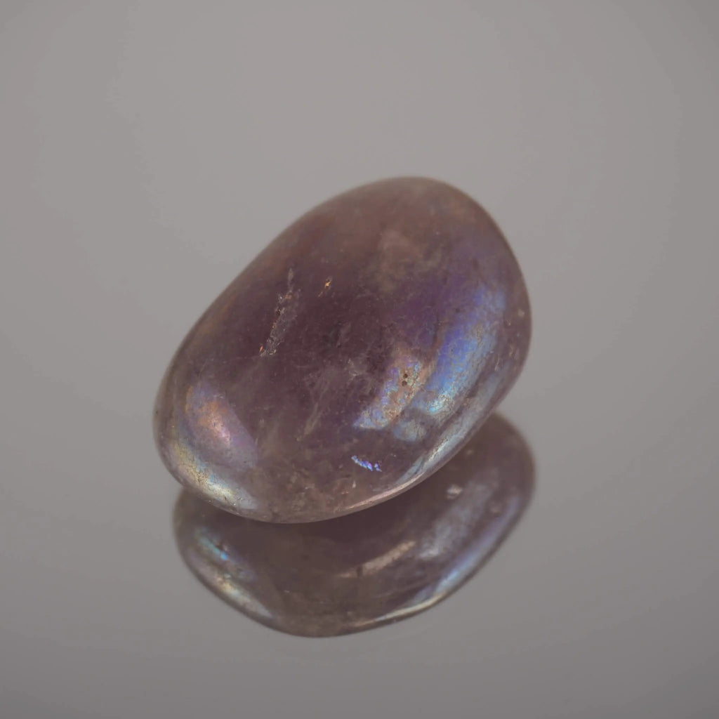 Lila Angel Aura Trommelstein mit Lichtreflexen auf spiegelnder Fläche