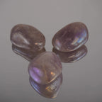 Drei Lila Angel Aura Trommelsteine mit schimmerndem Regenbogenglanz auf Spiegel arrangiert