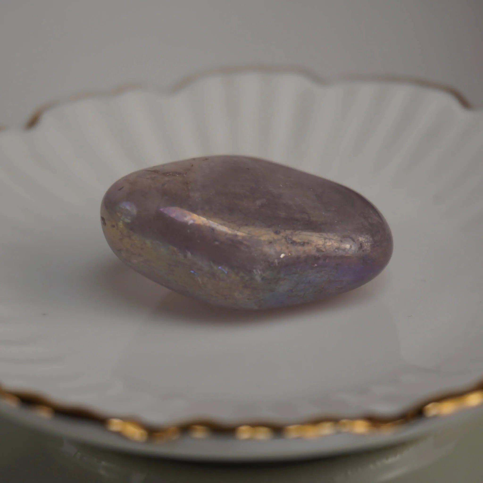 Lila Angel Aura Trommelstein auf weißem Teller mit Goldrand elegant präsentiert