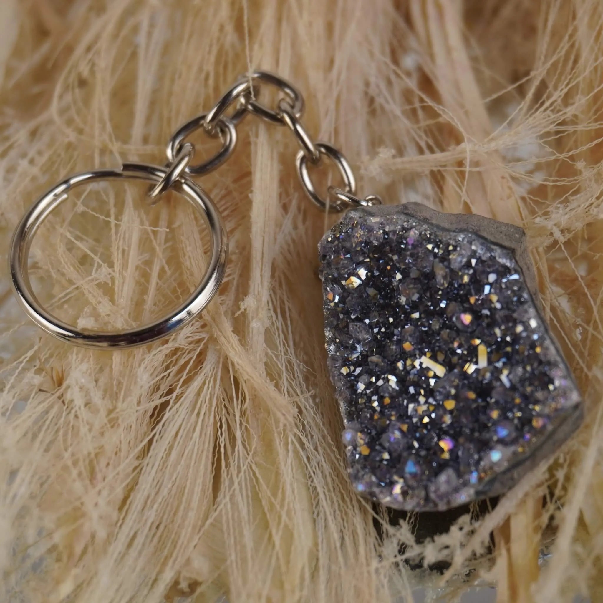 Glitzernder Lila Aqua Aura Druse Schlüsselanhänger auf hellen Naturfasern