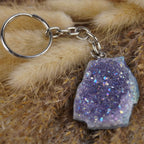 Lila Aqua Aura Druse Schlüsselanhänger mit silberfarbener Kette auf beigen Trockenpflanzen