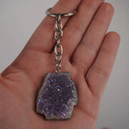 Lila Aqua Aura Druse Schlüsselanhänger mit Metallkette in einer Hand gehalten